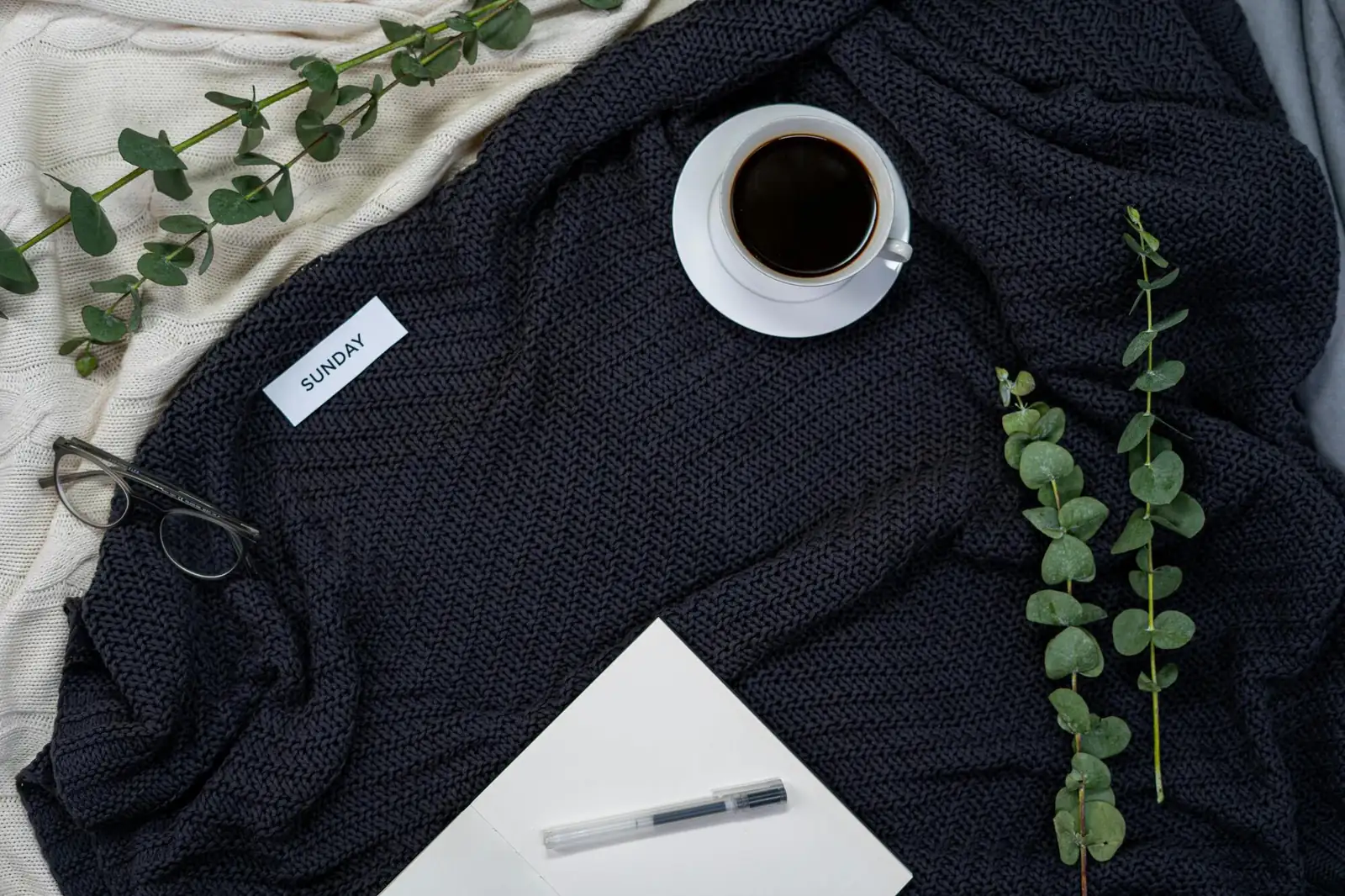 Coffee, a Bible, and greenery on a cozy blanket